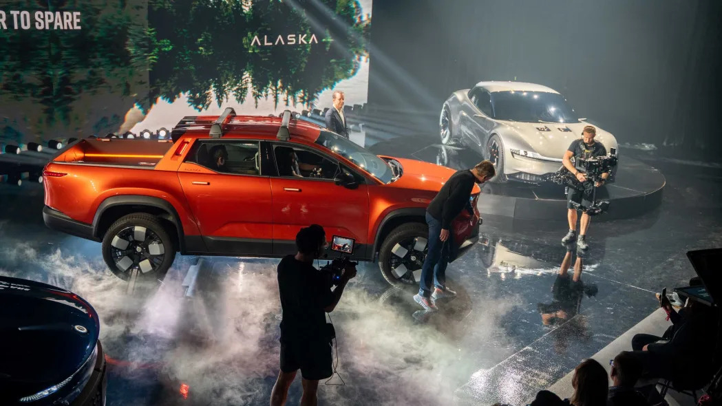 The orange Fisker Alaska electric pickup truck, on stage at an event.