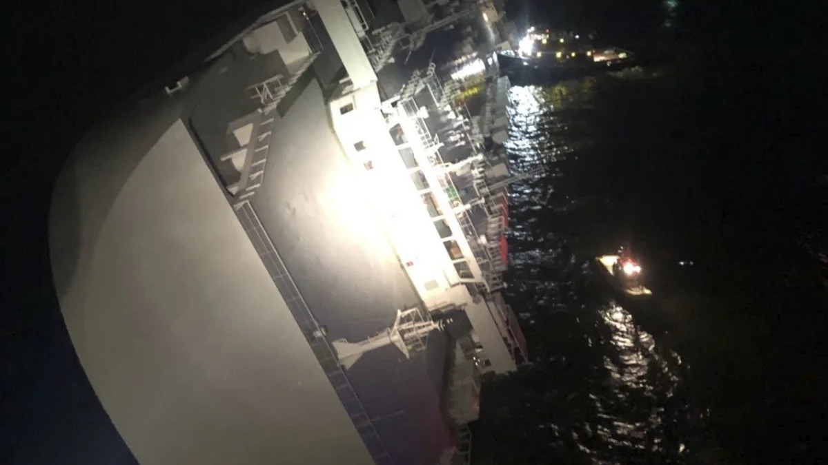 In this photo provided by the U.S. Coast Guard, the Golden Ray cargo ship lists to one side near a port on the Georgia coast, early Sunday, Sept. 8, 2019. The ship, carrying vehicles, was being evacuated after sharply listing. The U.S. Coast Guard said the vessel was leaving Brunswick when it somehow turned drastically sideways early Sunday. (U.S. Coast Guard via AP)