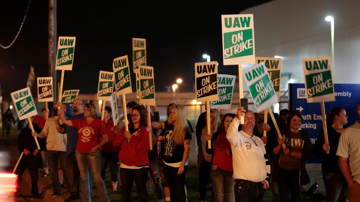 Members of the United Auto Workers (UAW) who are employed at the General Motors Co. Flint Assembly plant in Flint, Michigan, hold signs and react as workers drive out of the plant as they go on strike early on September 16, 2019. - The United Auto Workers union began a nationwide strike against General Motors on September 16, with some 46,000 members walking off the job after contract talks hit an impasse. (Photo by JEFF KOWALSKY / AFP)        (Photo credit should read JEFF KOWALSKY/AFP/Getty Images)