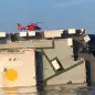 In this image released by the U.S. Coast Guard, a USCG helicopter hovers over an overturned cargo ship in St. Simons Sound, Ga., Monday, Sept. 9, 2019. The U.S. Coast Guard says rescuers have heard noises from inside the ship where multiple crew members are missing after their huge vessel overturned and caught fire off Georgia's coast.   (U.S. Coast Guard via AP)