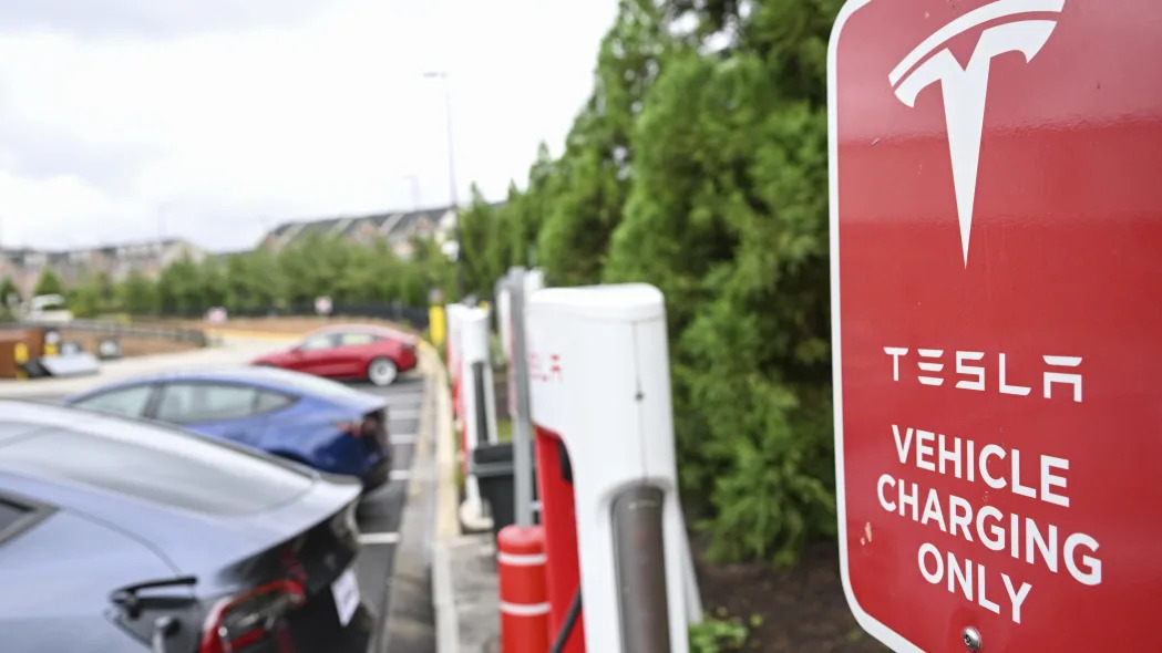 Several Tesla vehicles charge next to a sign that says "Tesla vehicle charging only"