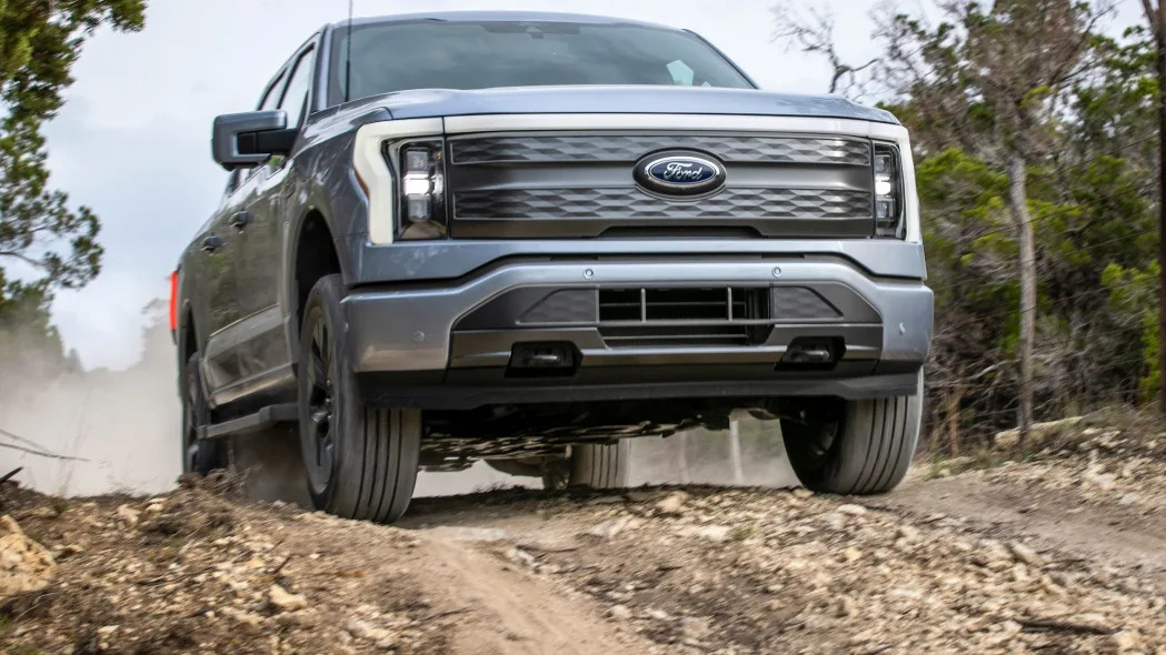 The 2022 Ford F-150 Lightning Lariat driving on a dirt road.