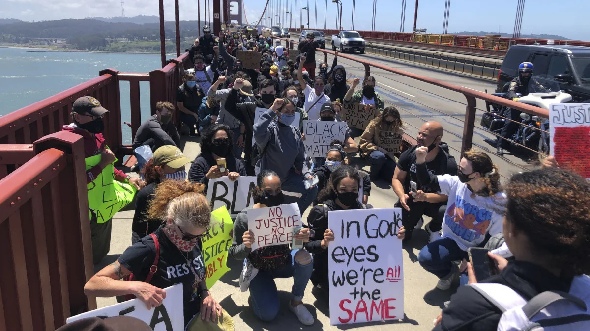 Dozens of people kneel after marching across the Golden Gate Bridge in support of the Black Lives Matter movement in San Francisco Saturday, June 6, 2020. People are protesting the death of George Floyd, who died after he was restrained by Minneapolis police on May 25 in Minnesota. (AP Photo/Jeff Chiu)