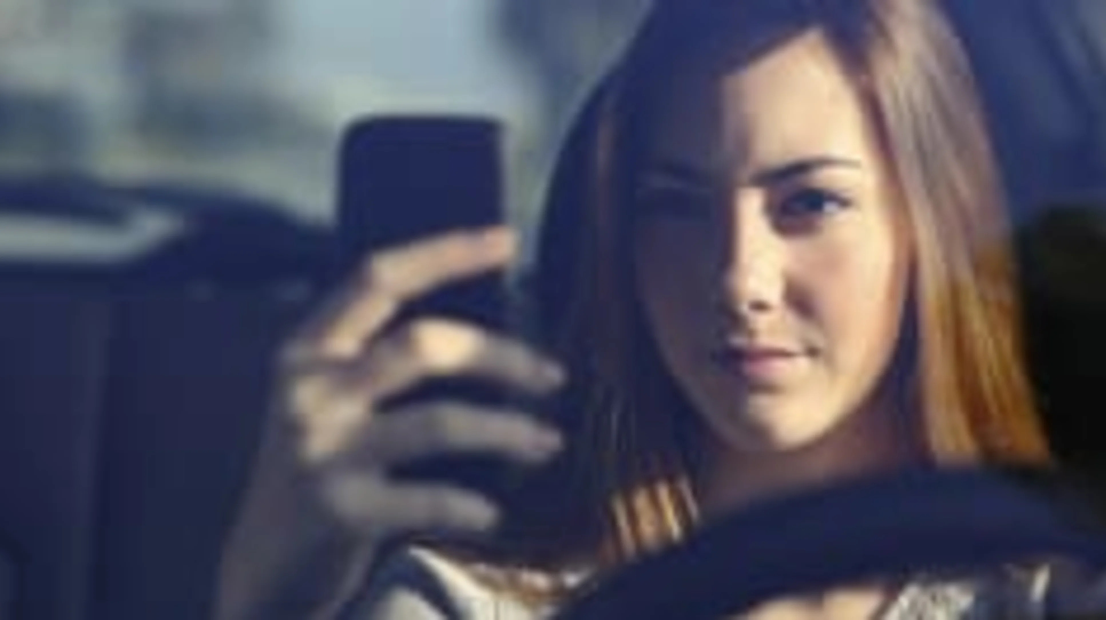 Front view of woman driving and typing on smart phone