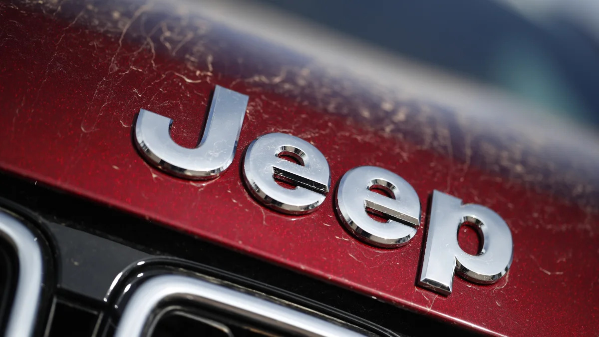 In this Sunday, April 15, 2018, photograph, the company logo shines on the leading edge of a hood of an unsold 2018 Grand Cherokee on a Jeep dealer's lot in the south Denver suburb of Englewood, Colo. (AP Photo/David Zalubowski)