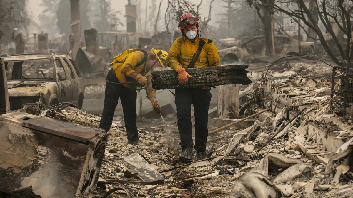 Jackson County District 5 firefighter Captain Aaron Bustard, right, and Andy Buckingham work on a smoldering fire in a burned neighborhood as destructive wildfires devastate the region on Friday, Sept. 11, 2020, in Talent, Ore. (AP Photo/Paula Bronstein)