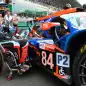 Oreca 07-Gibson LMP2's Japanese driver Takuma Aoki poses next to his car in the grid prior to the 89th edition of the Le Mans 24 Hours endurance race, in Le Mans, northwestern France, on August 21, 2021. - On the initiative of Frederic Sausset, the first quadruple amputee pilot who raced at Le Mans in 2016, Oreca 07-Gibson LMP2 is driven by two paraplegic pilots, Japanese Takuma Aoki and Belgian Nigel Bailly. (Photo by JEAN-FRANCOIS MONIER / AFP) (Photo by JEAN-FRANCOIS MONIER/AFP via Getty Images)