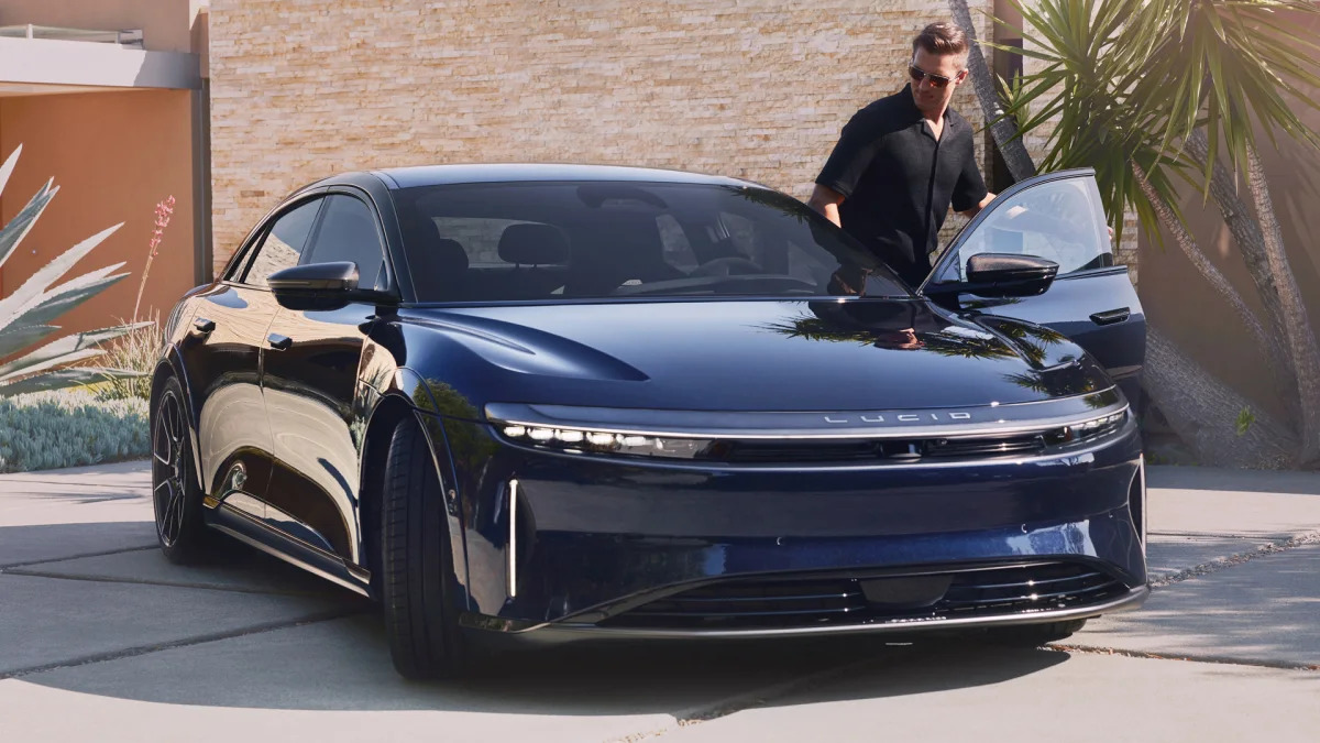 Lucid Air Sapphire lifestyle tech man dressed in black getting into car with wheels pointed wrong way