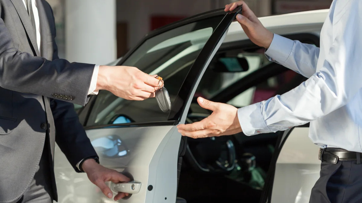 Salesman's hands giving key to male customer