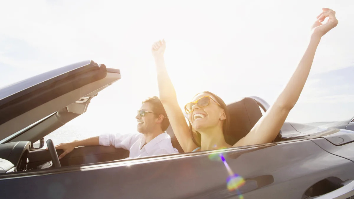 Couple driving in convertible under sunny sky