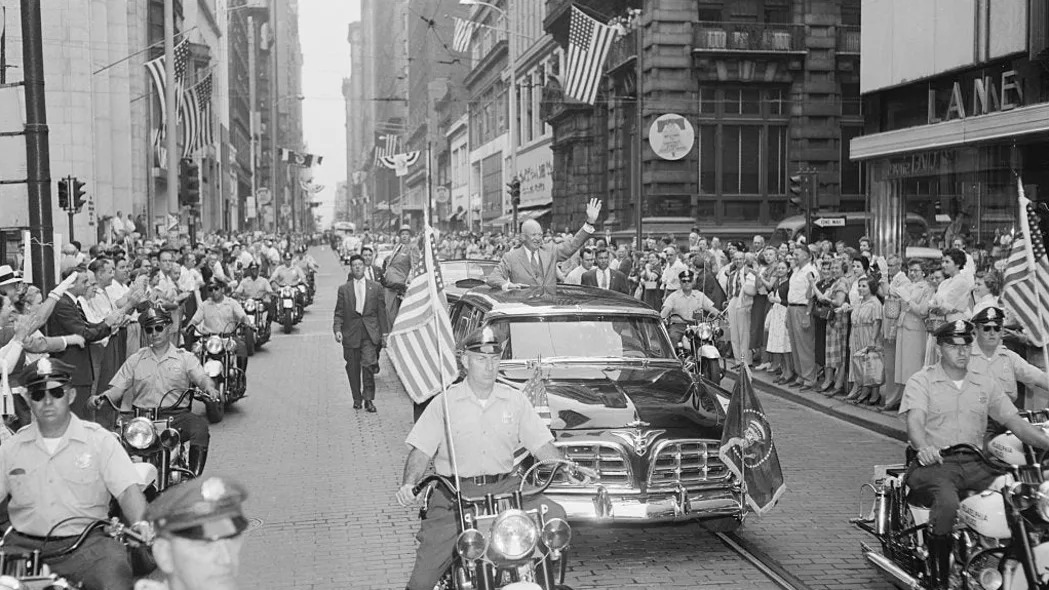 President Dwight Eisenhower waves from the presidential limousine