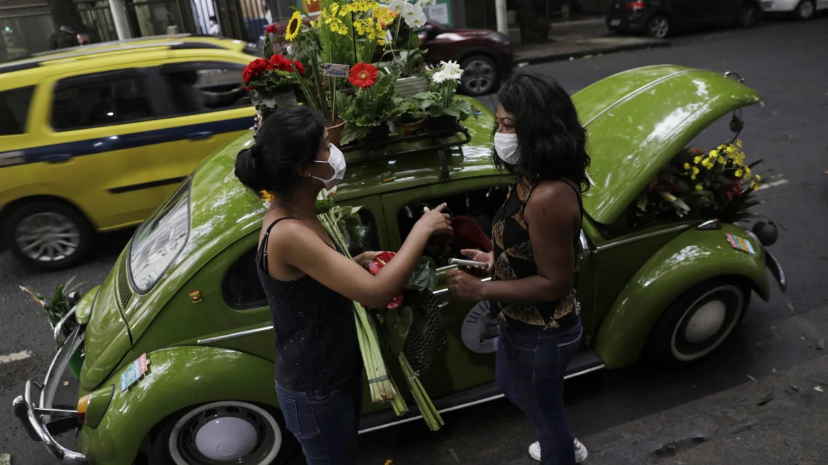 Valcineia Machado, also known as Roberta, sells flowers to a customer next to her car which she transformed to a mobile flower shop after loosing her business amid the coronavirus disease (COVID-19) outbreak, in Rio de Janeiro, Brazil, October 8, 2020. Picture taken on October 8, 2020. REUTERS/Ricardo Moraes