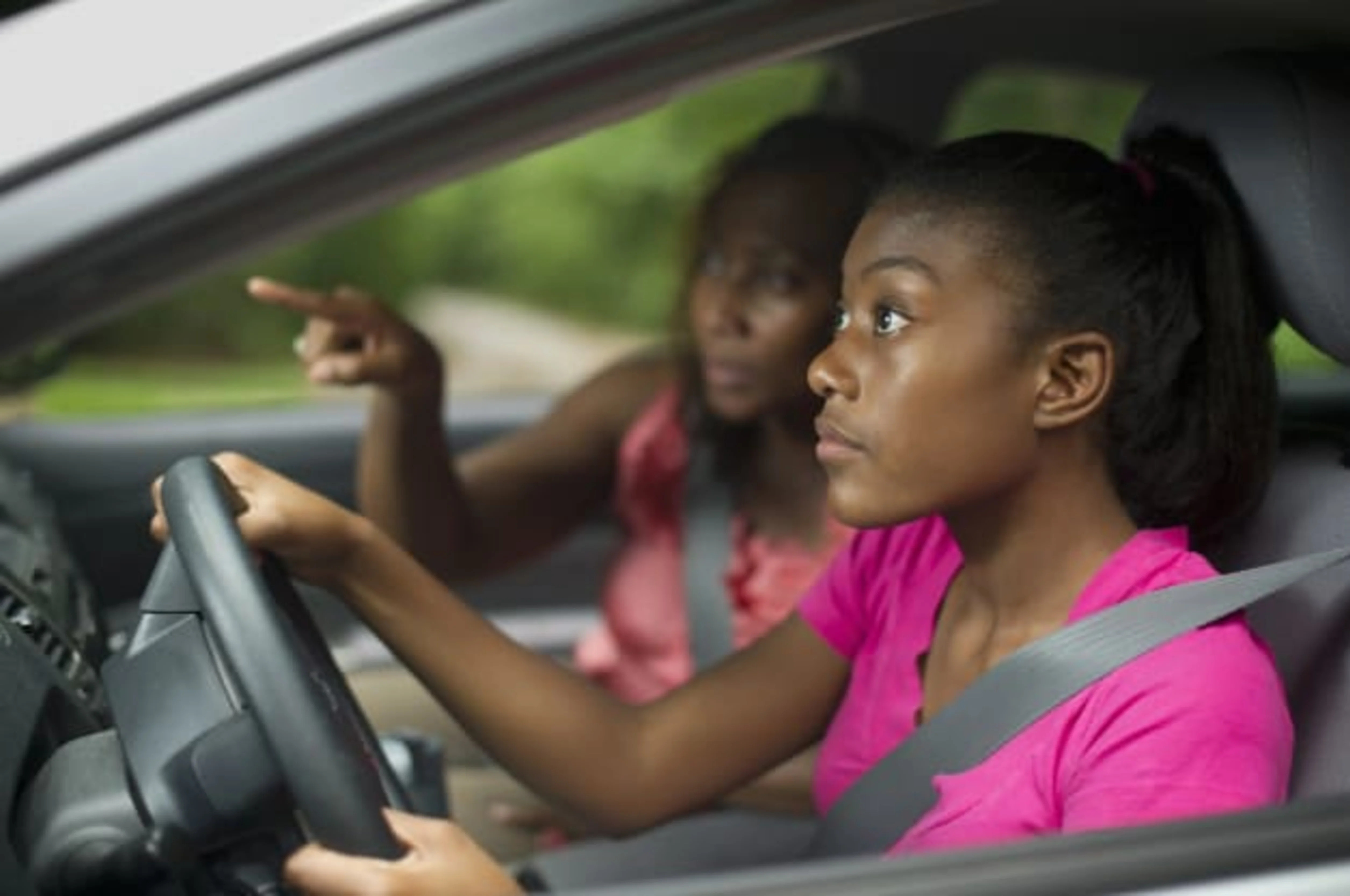 African American teen learning to drive with mom