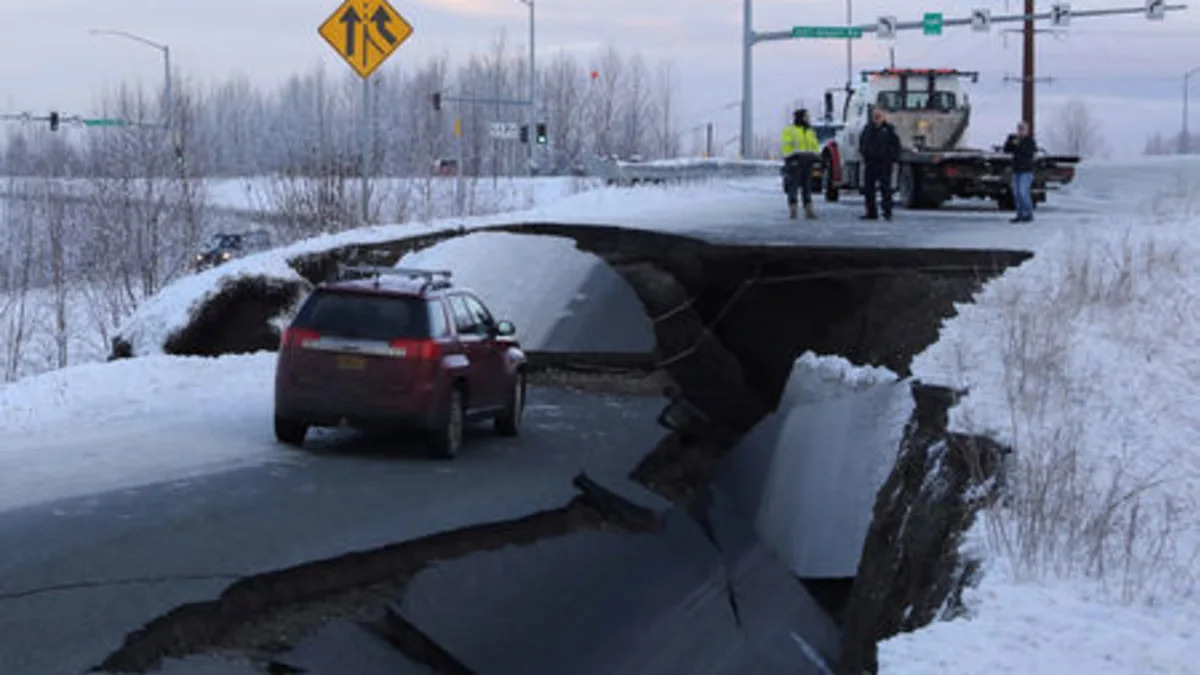 A stranded vehicle lies on a collapsed roadway near the airport after an earthquake in Anchorage