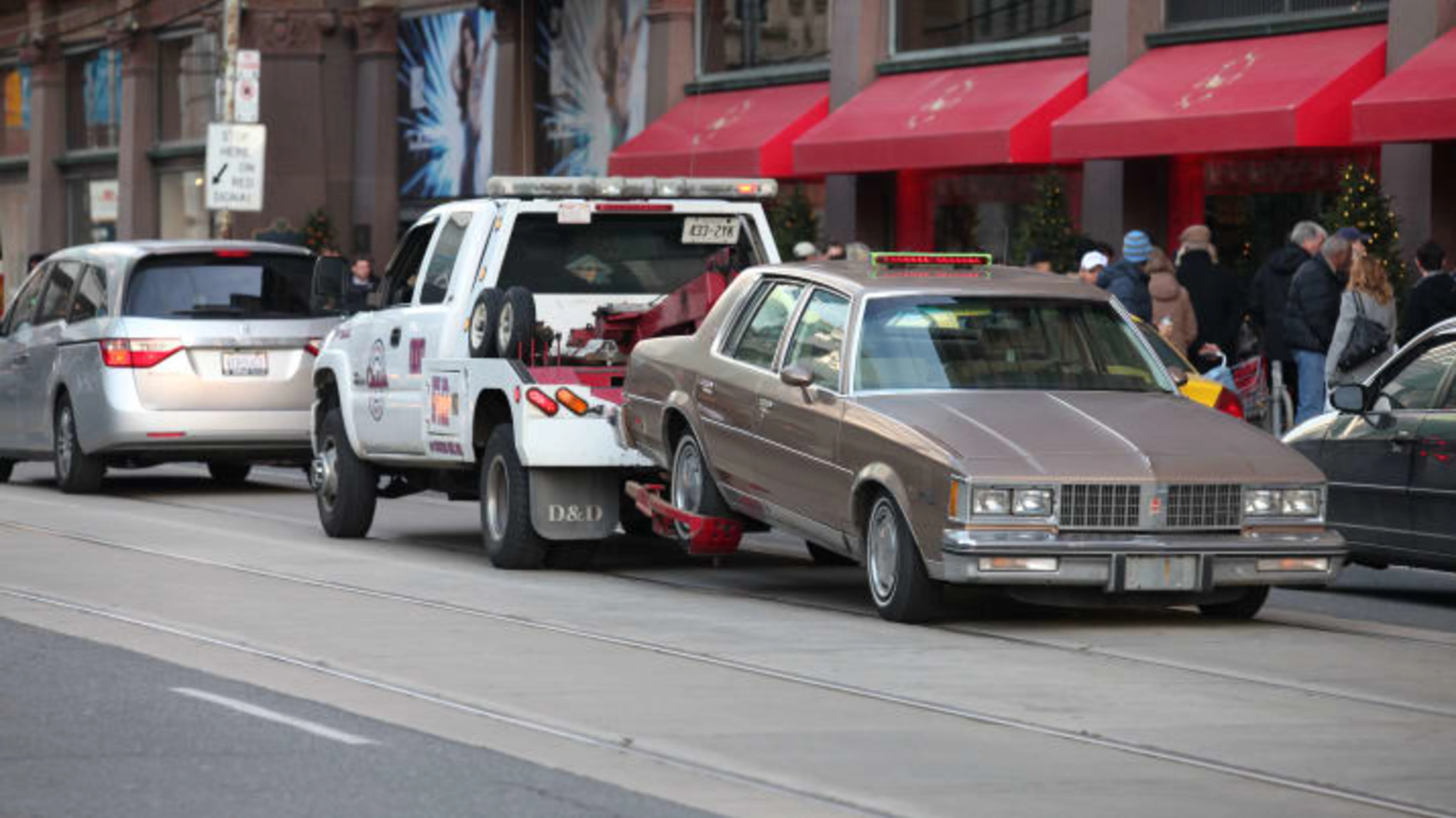 Tow truck  hauling a car on street in downtown Toronto Canada